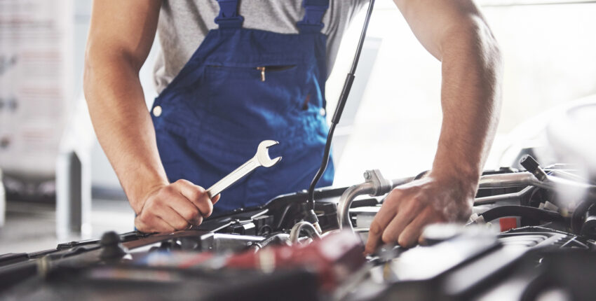 Professional car mechanic diagnosing engine issues with tools
